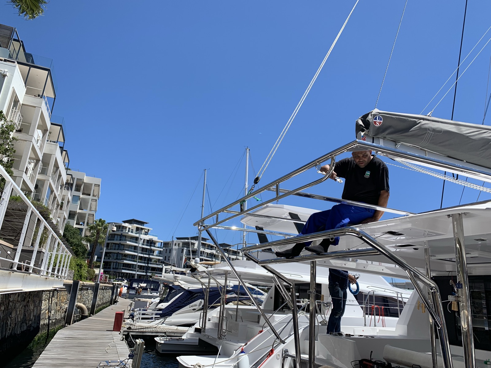 Running wiring through the solar arch, high above the cockpit with the V&A marina below