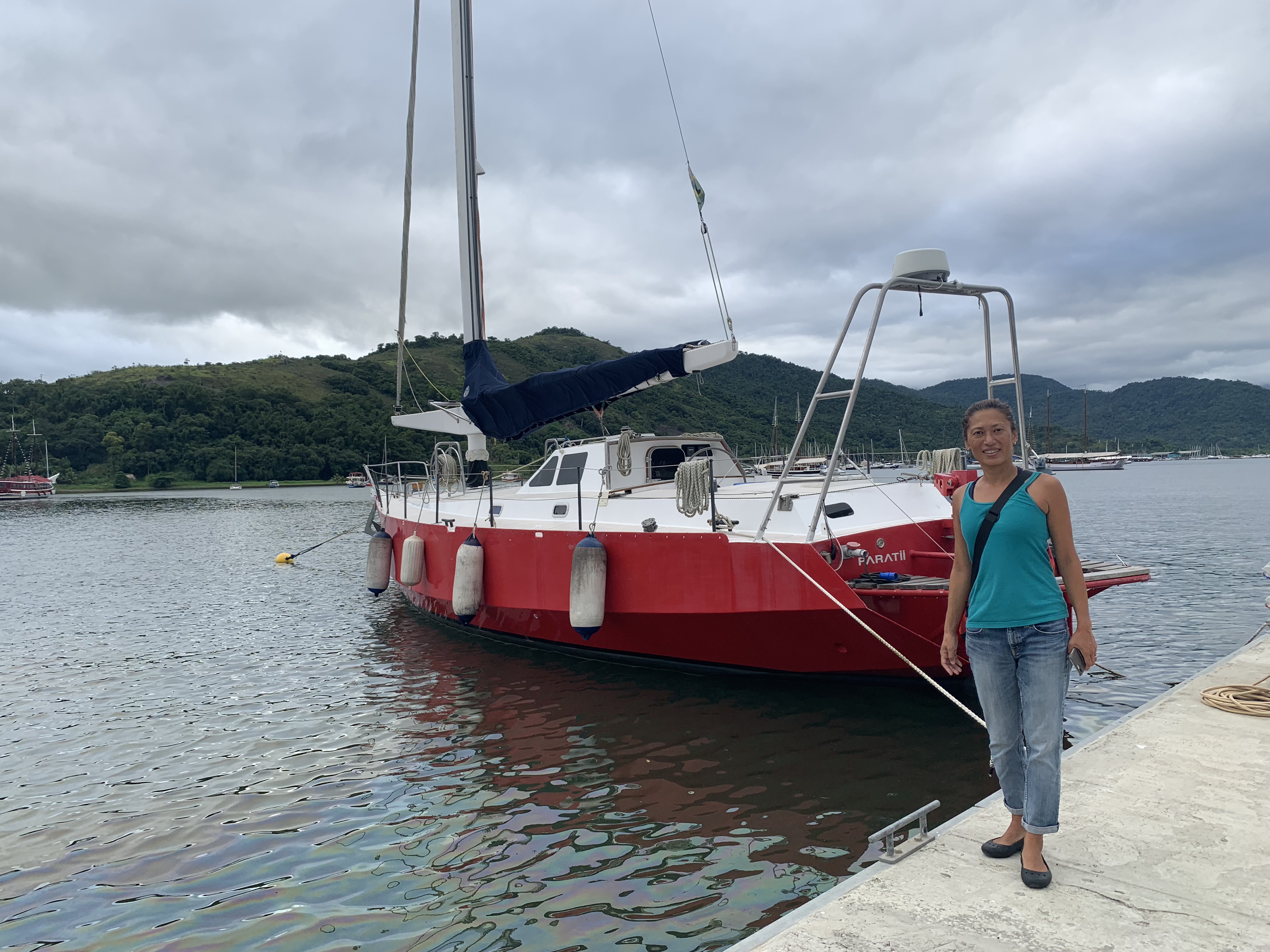 Yuka standing alongside Paratii, Amyr Klink's red-hulled boat, at Marina do Engenho