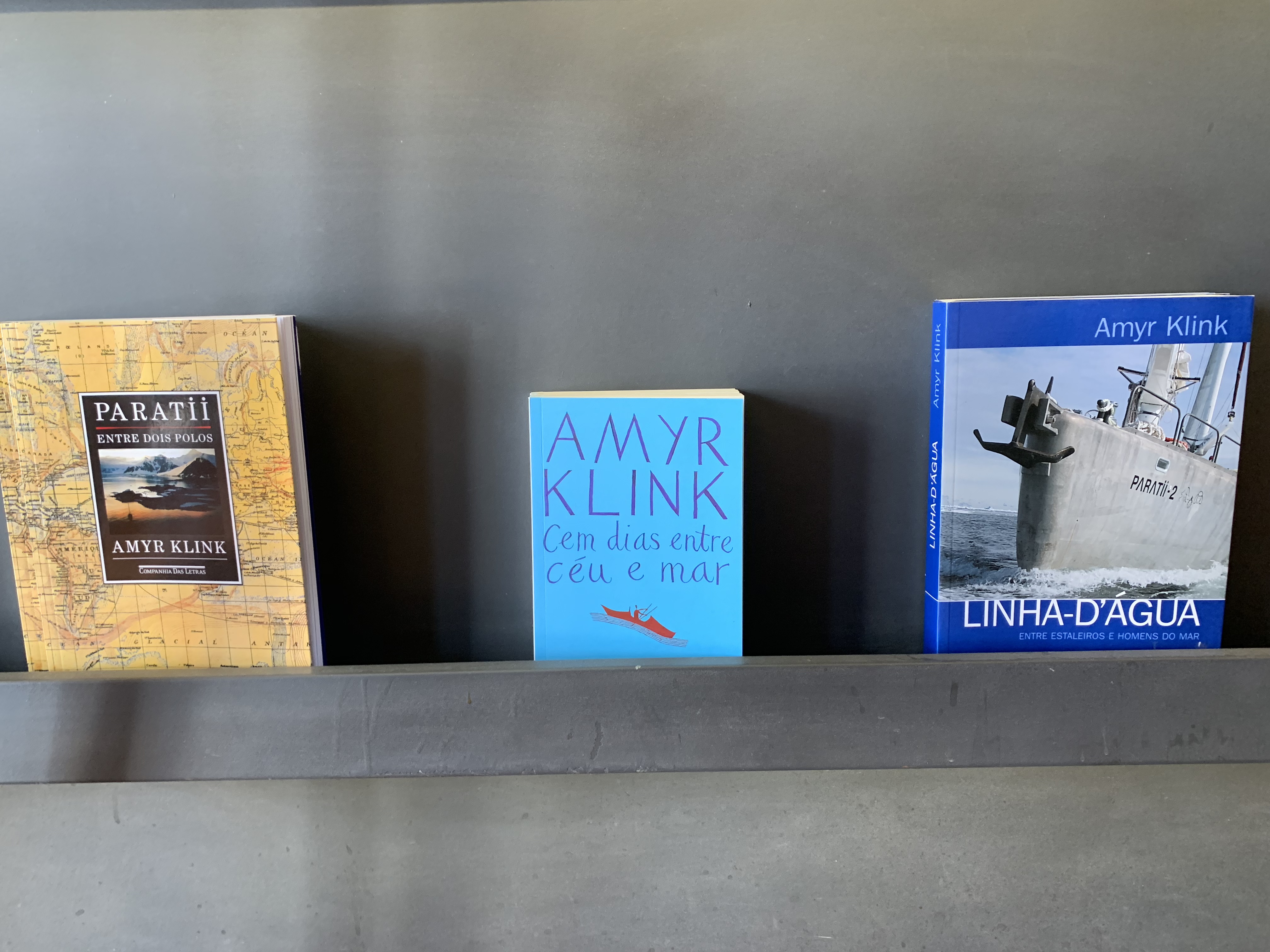 Three Amyr Klink books on a shelf: Paratií Entre Dois Polos, Cem dias entre céu e mar, and Linha-D'Água