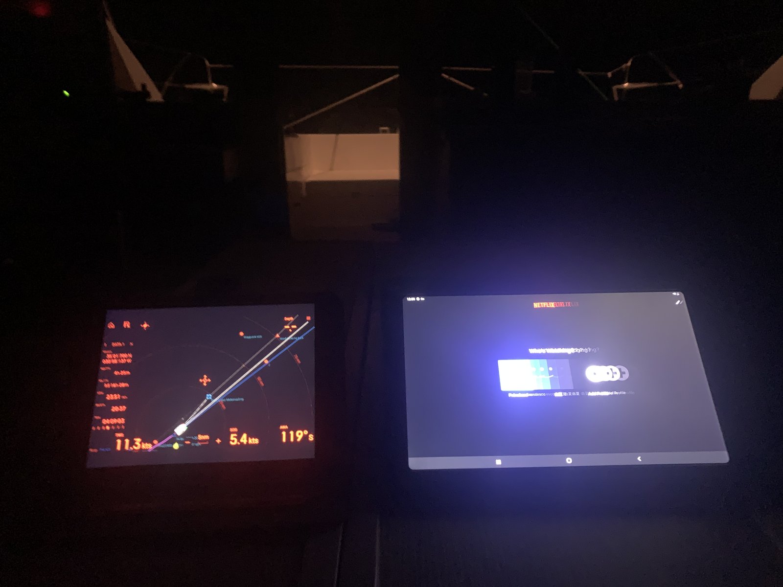 Two screens at midnight: AIS tracking a cargo ship on the left, The Kominsky Method on the right. This is what offshore sailing actually looks like after week two.