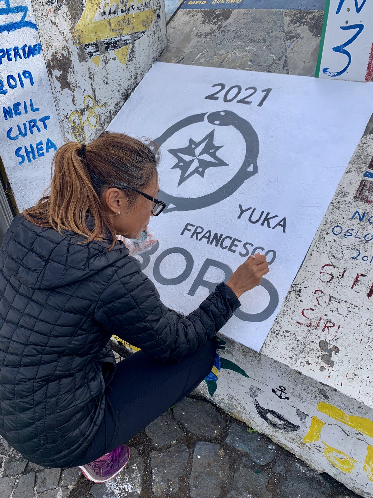 Yuka painting the Oroboro mural on the Horta breakwater — June 2021.