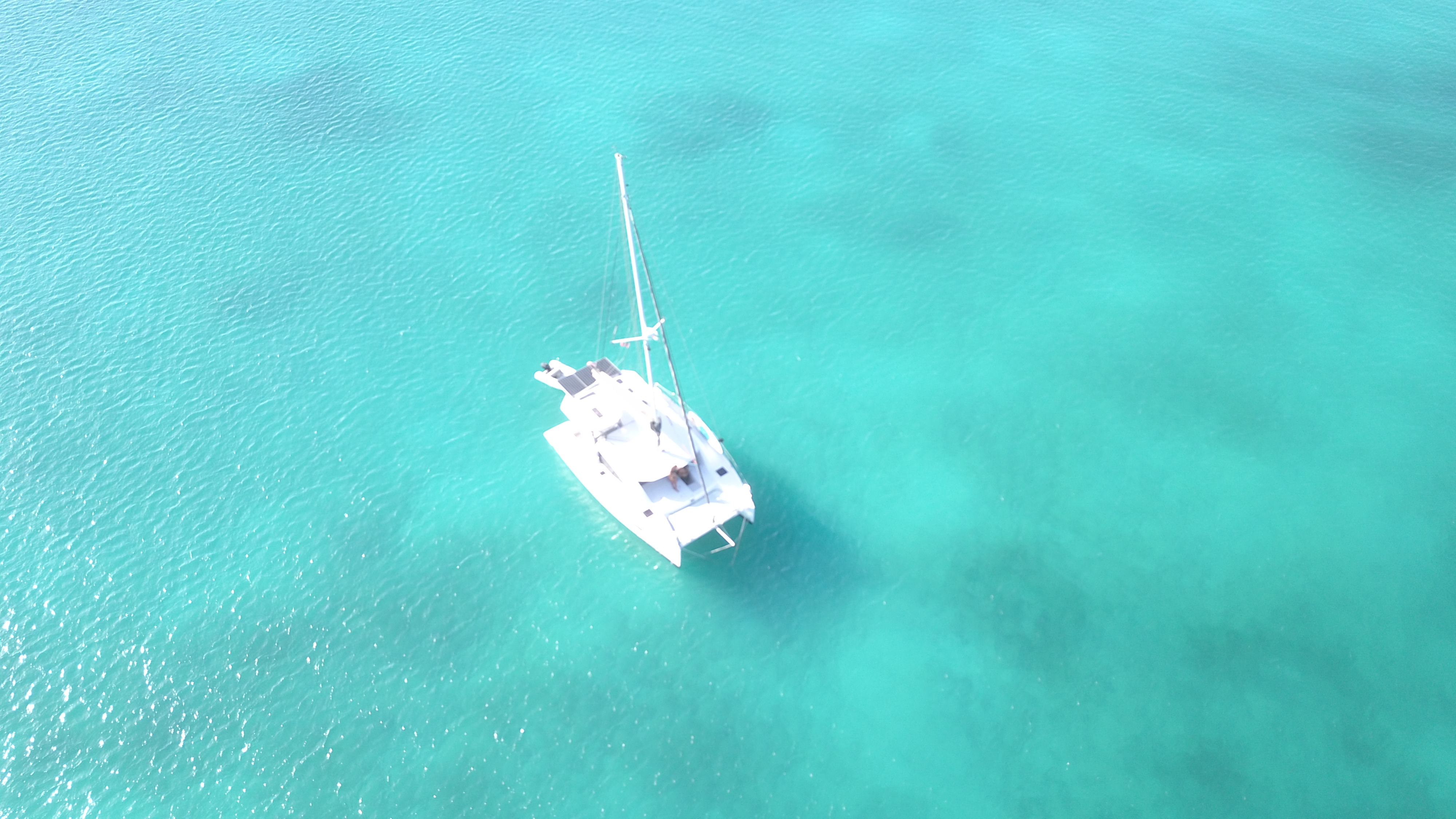 Oroboro alone in Barbuda's turquoise water — drone top-down view