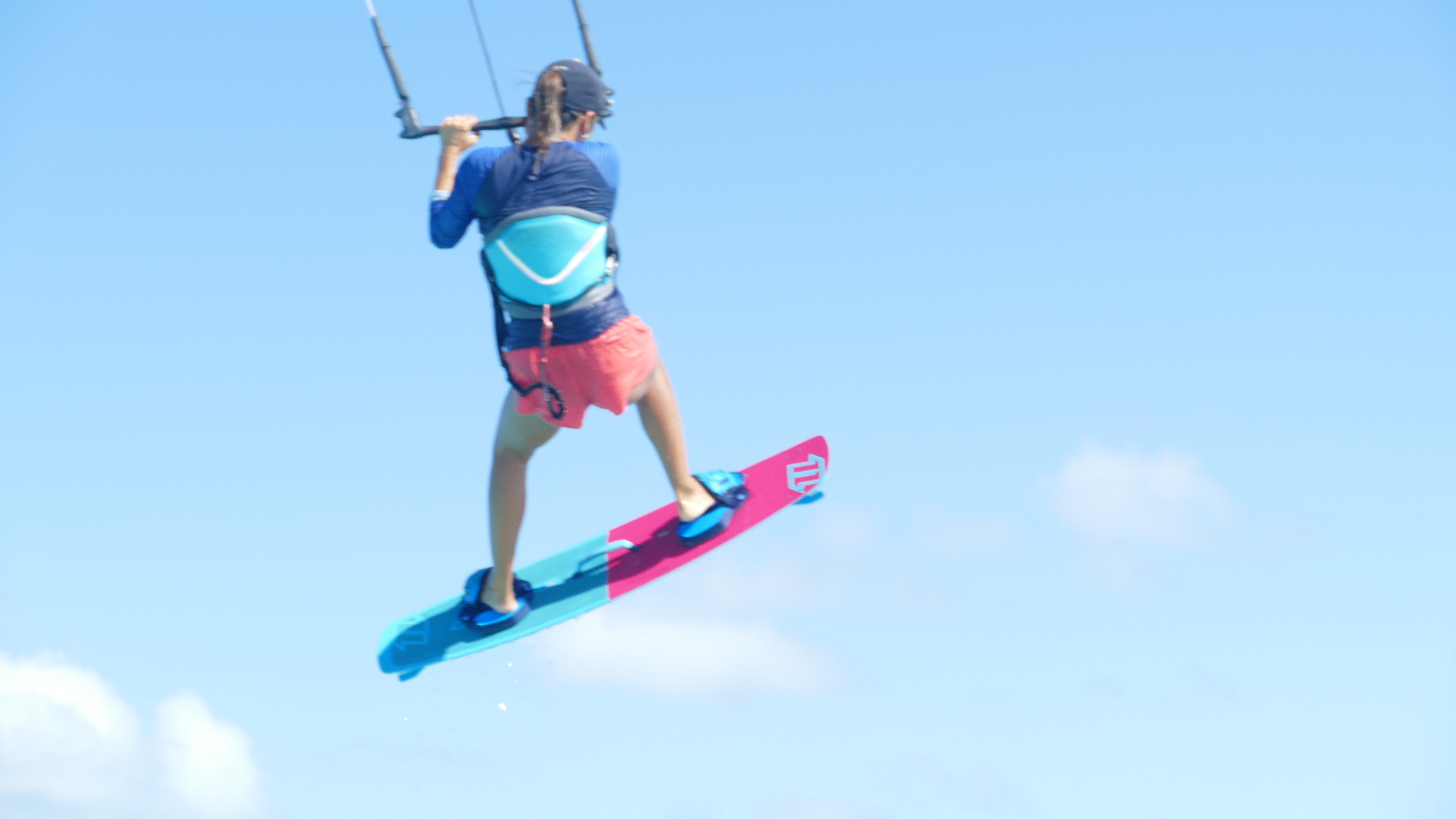 Yuka in flight with her pink board, clear blue sky
