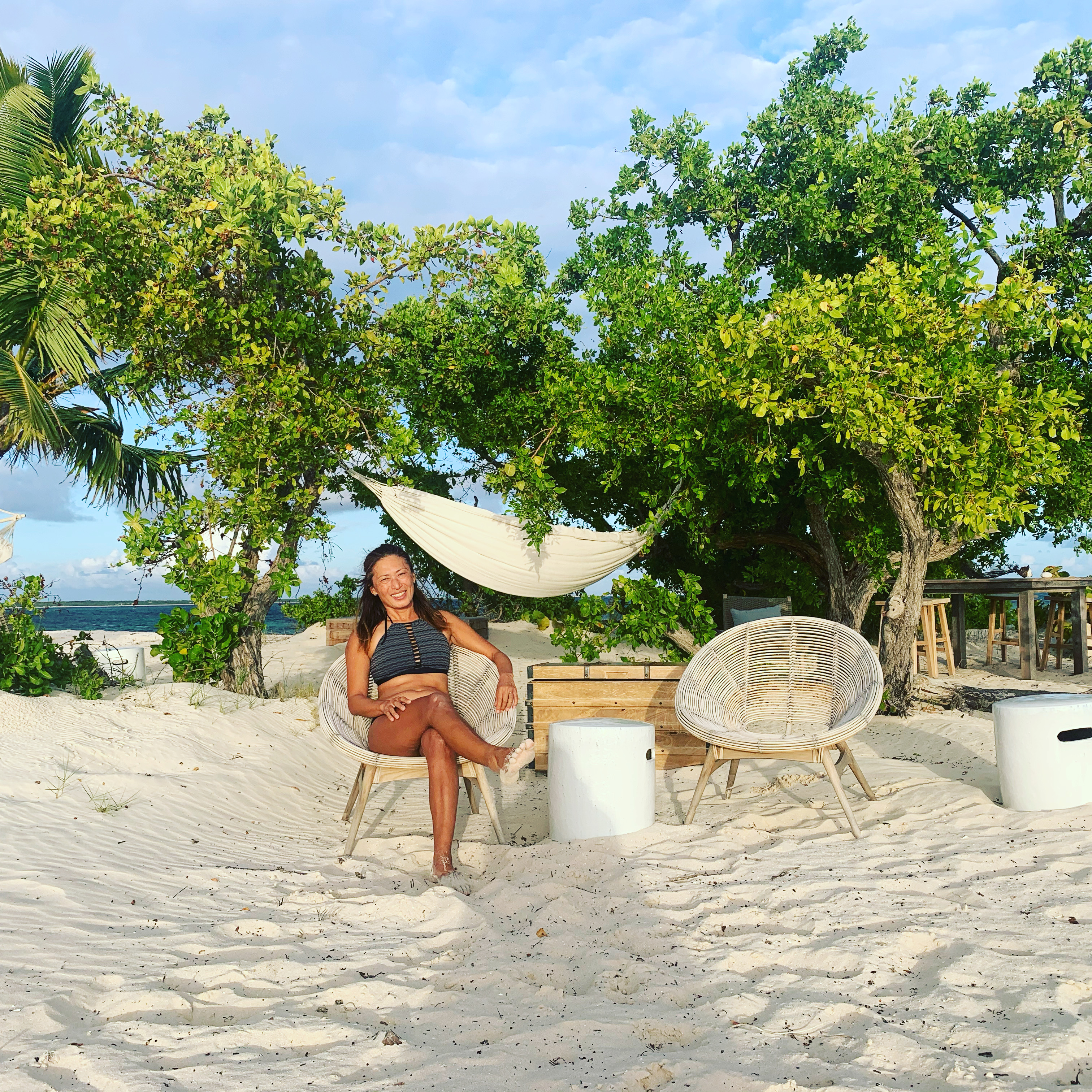 Yuka in a beach chair on Barbuda's white sand at golden hour