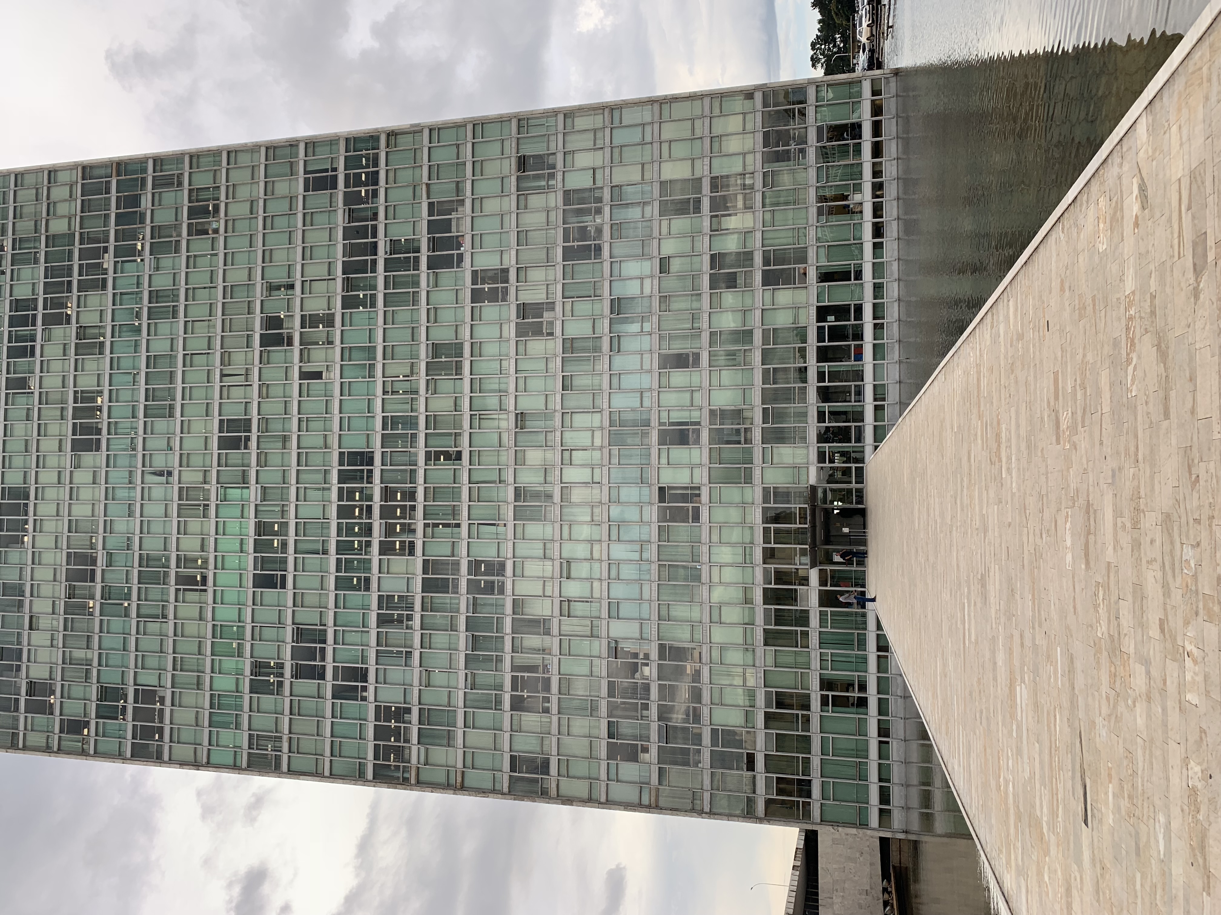 Close-up de uma das torres do Congresso Nacional — fachada de vidro verde encontrando o concreto