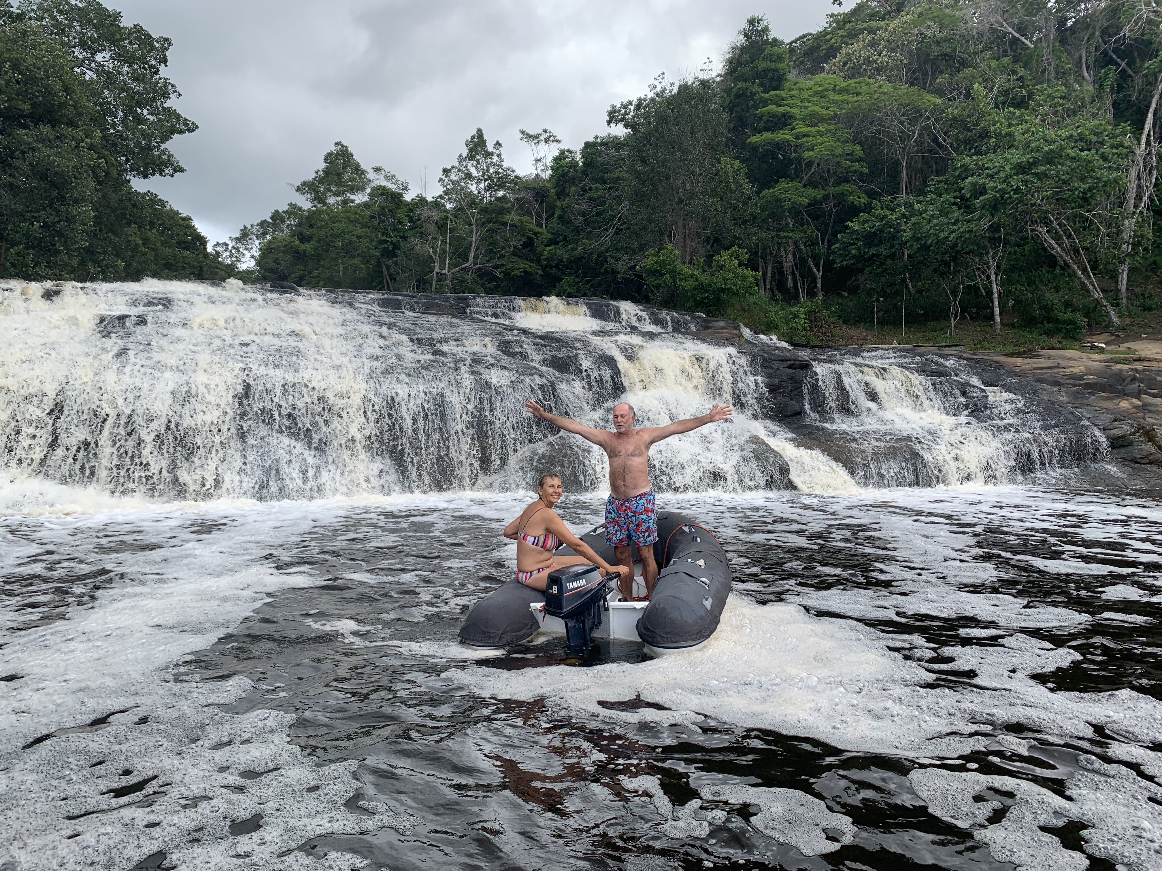 Francesco and Yuka standing next to the dinghy in front of the main waterfall cascade