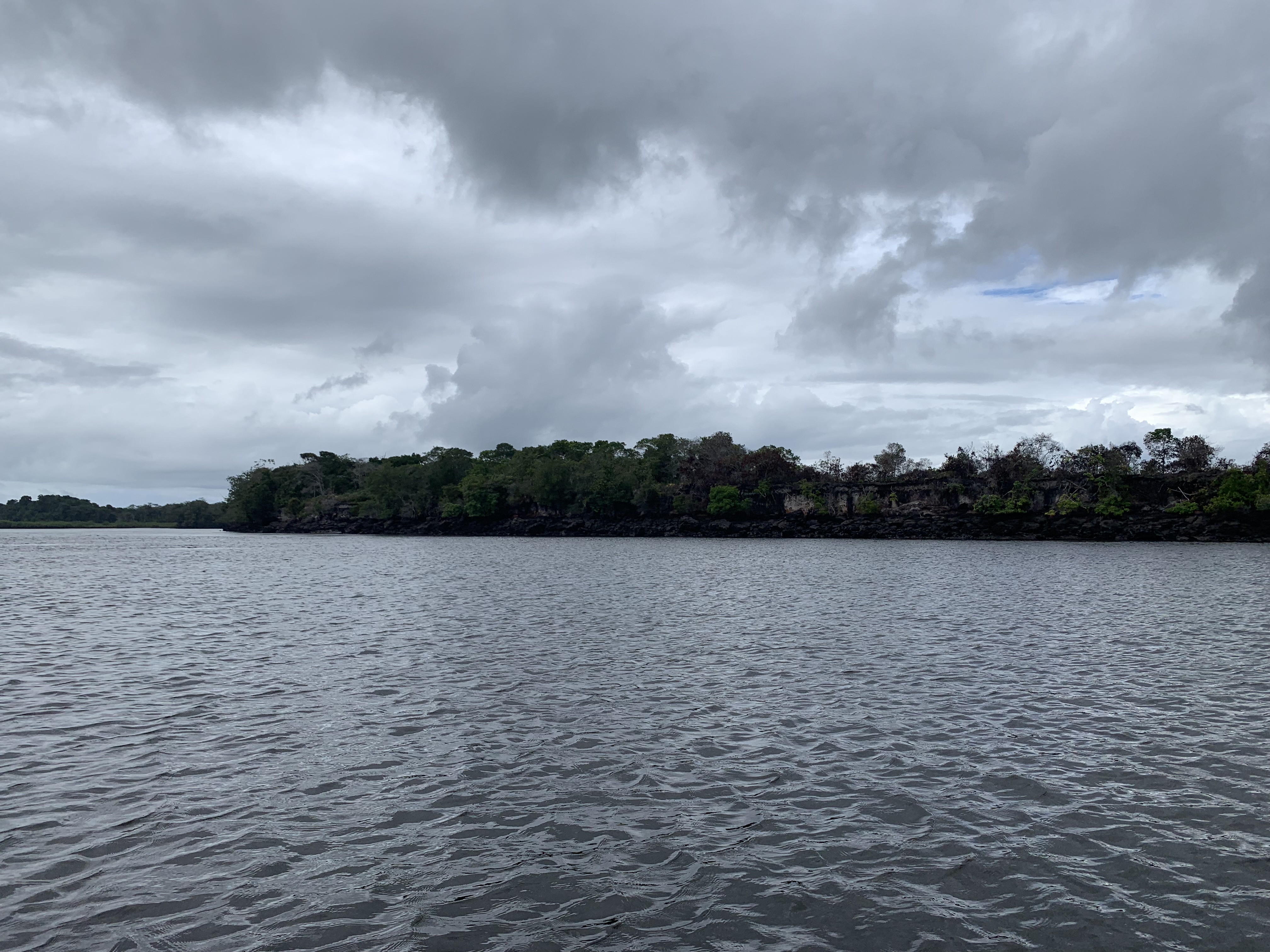Dark river between rocky cliffs with dramatic storm clouds above, Serra Grande, Bahia