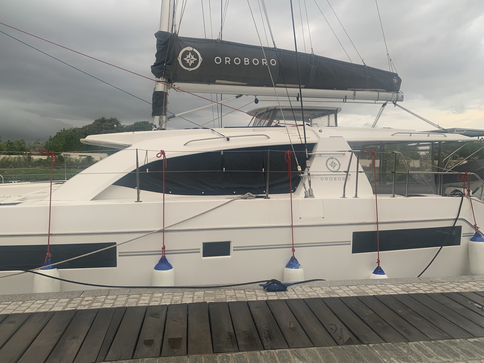 Oroboro double-lashed with red storm lines at the Canouan dock — Gonzalo's dark clouds building overhead