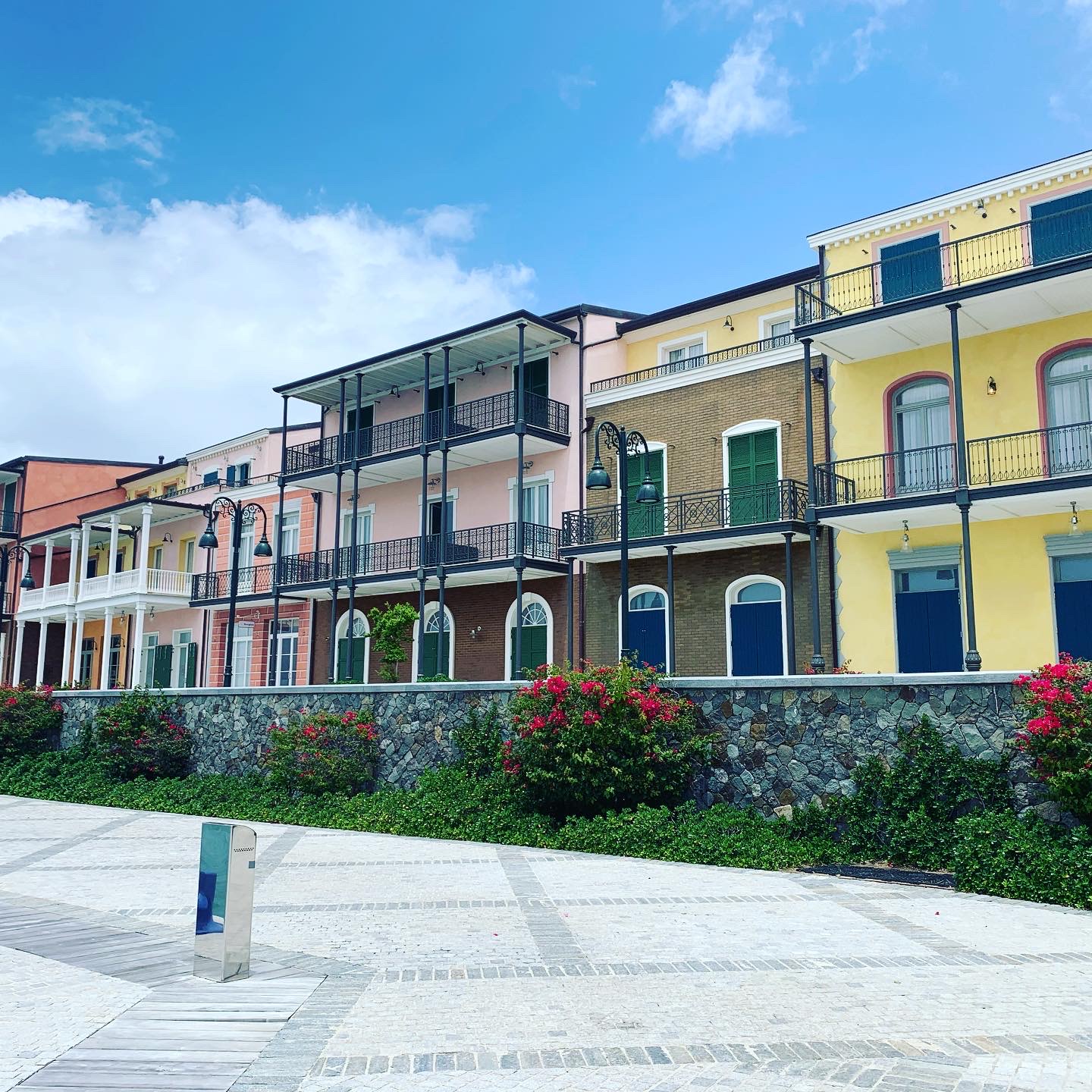 The Canouan marina's colonial-style resort villas — pink, yellow, and brick facades with iron balconies and flower gardens
