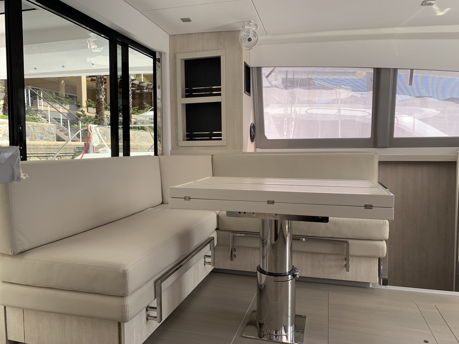 The saloon — L-shaped settee, folding table, and full-height windows