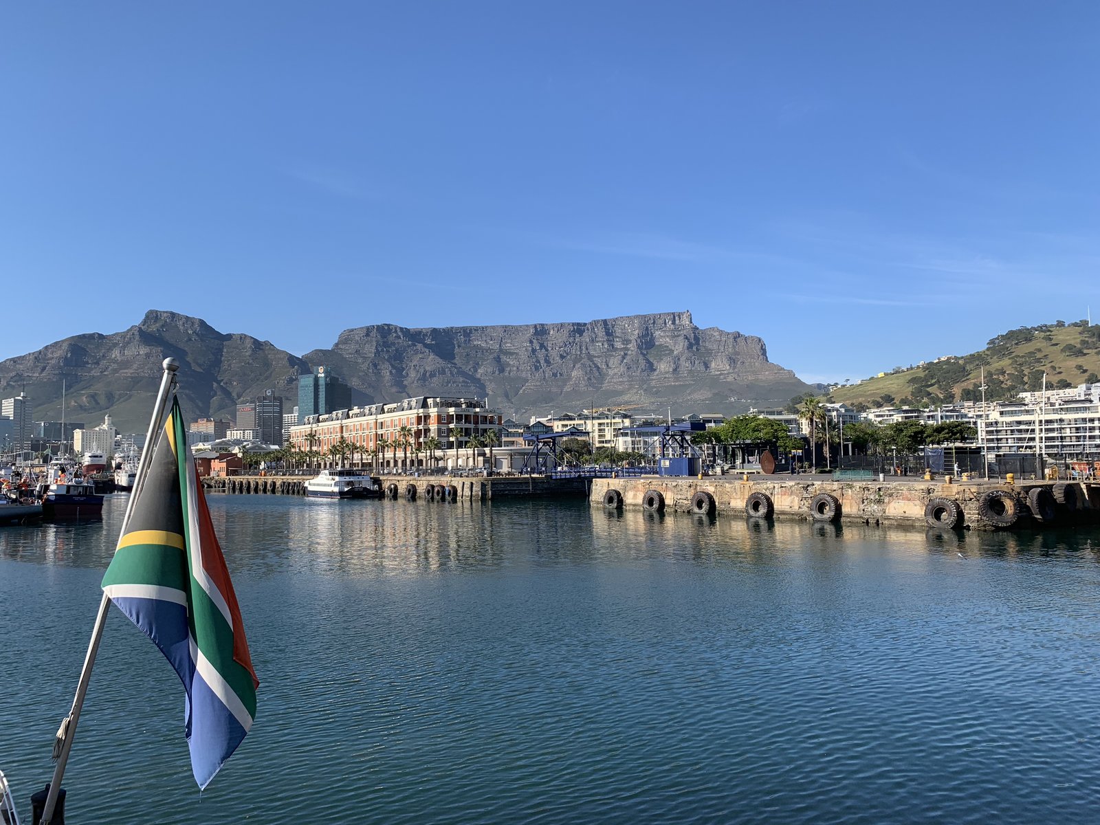 The South African flag flying in front of Table Mountain from the water