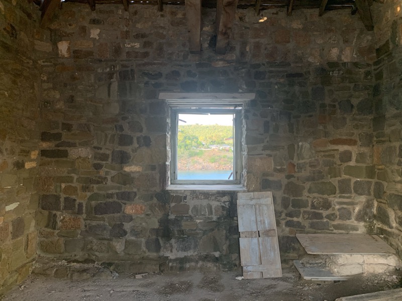 Inside an old stone ruin at English Harbour — a window frames the harbour beyond
