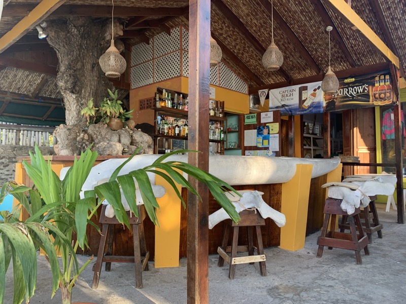 A Bequia waterfront beach bar — open-air thatched roof with Sparrow's Rum and Captain Blugh XO on the shelf