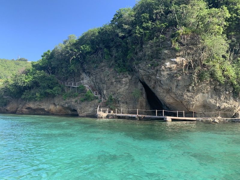 A sea cave with a wooden dock walkway in Bequia — crystal clear turquoise water at the entrance