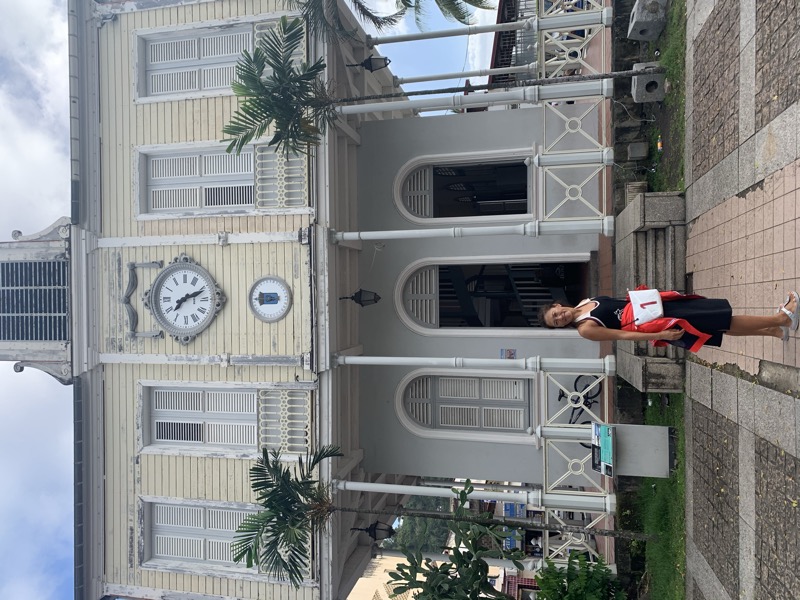 Yuka in front of a beautiful colonial-style French Caribbean town hall building