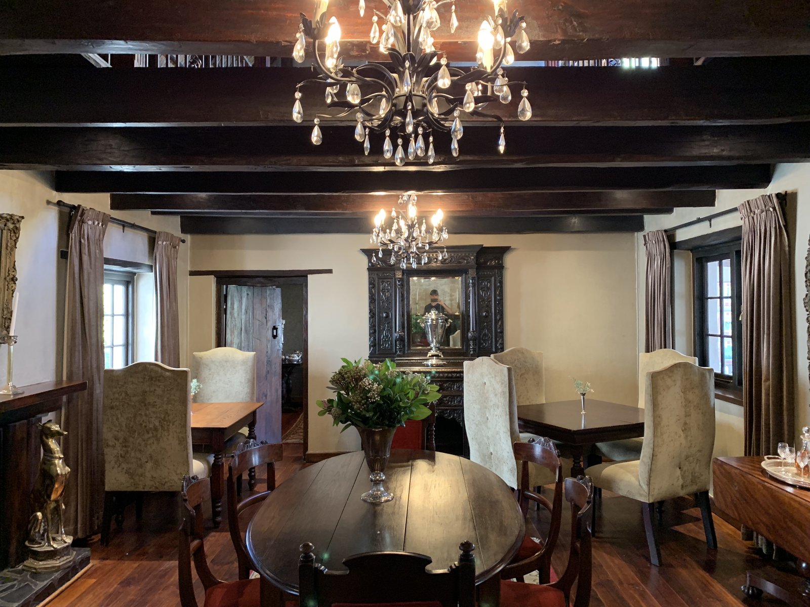 The Zinzi restaurant dining room — dark timber beams, crystal chandeliers, and candlelit tables
