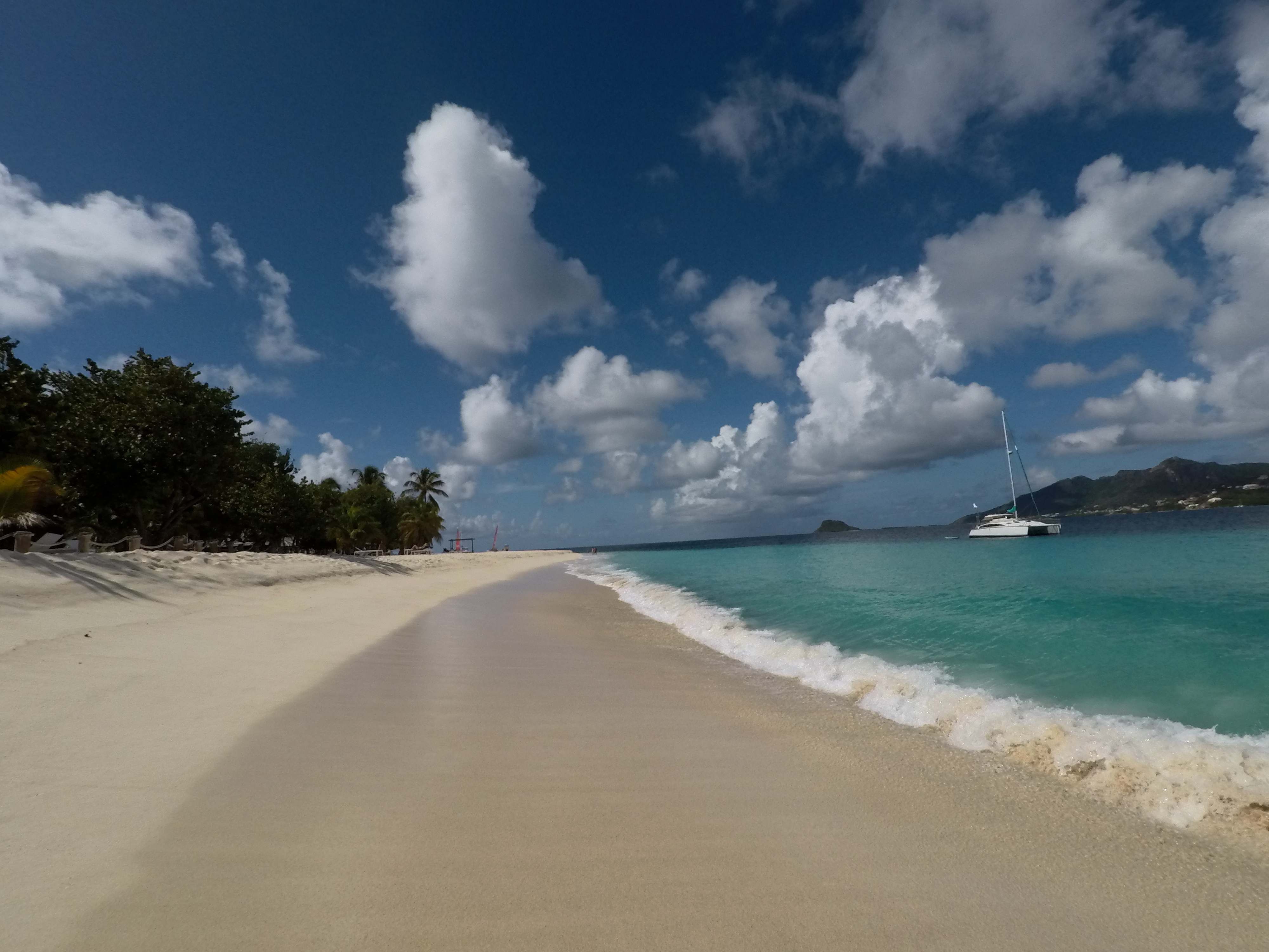 An empty beach with Oroboro anchored just beyond the surf