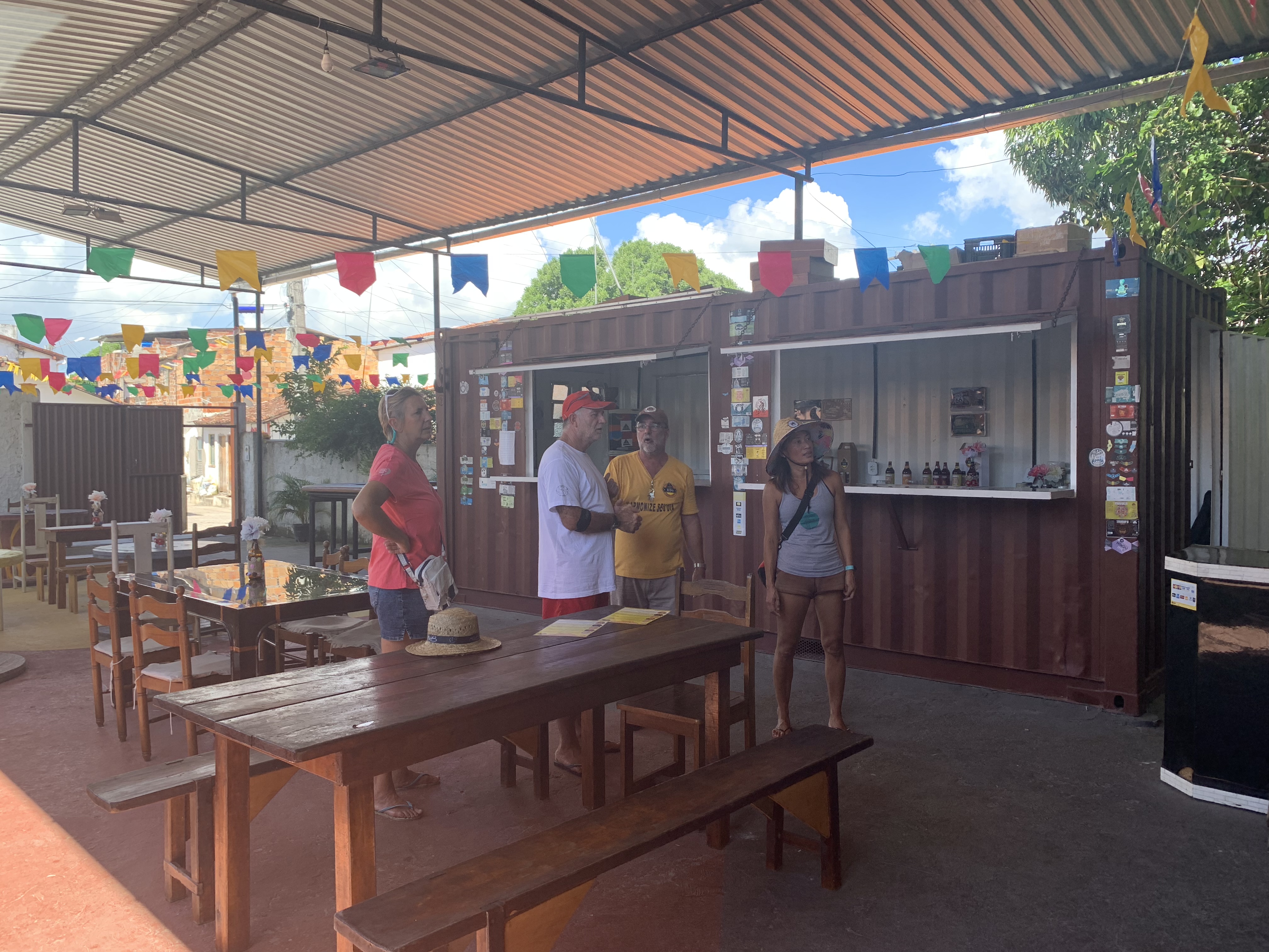 O grupo dentro do bar ED3 com o balcão de contêiner e as decorações de Festa Junina