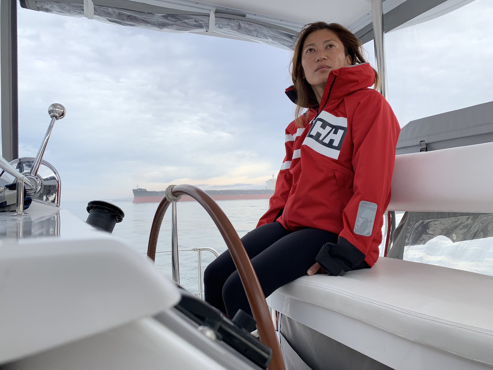 Yuka at the helm during the Langebaan shake-down, a cargo ship on the horizon