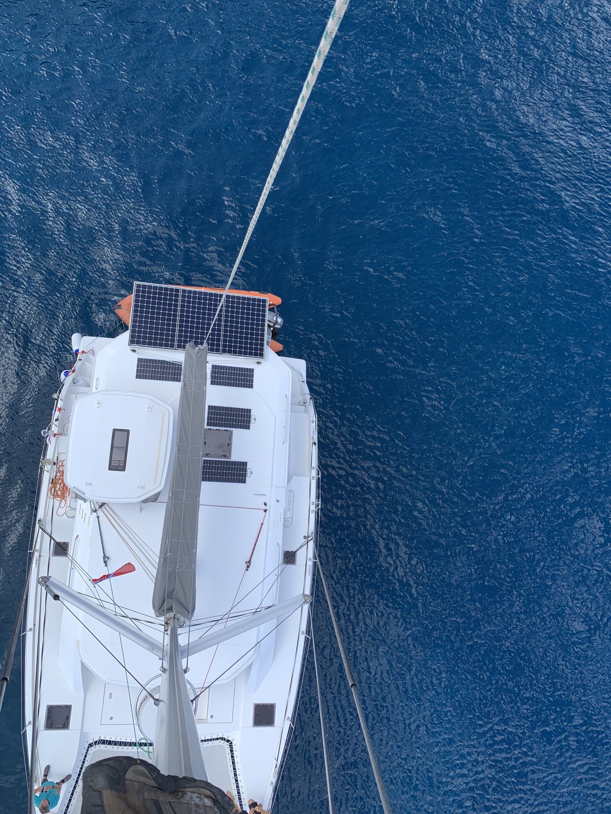 Oroboro from the masthead — solar panels covering the coachroof, open ocean in every direction