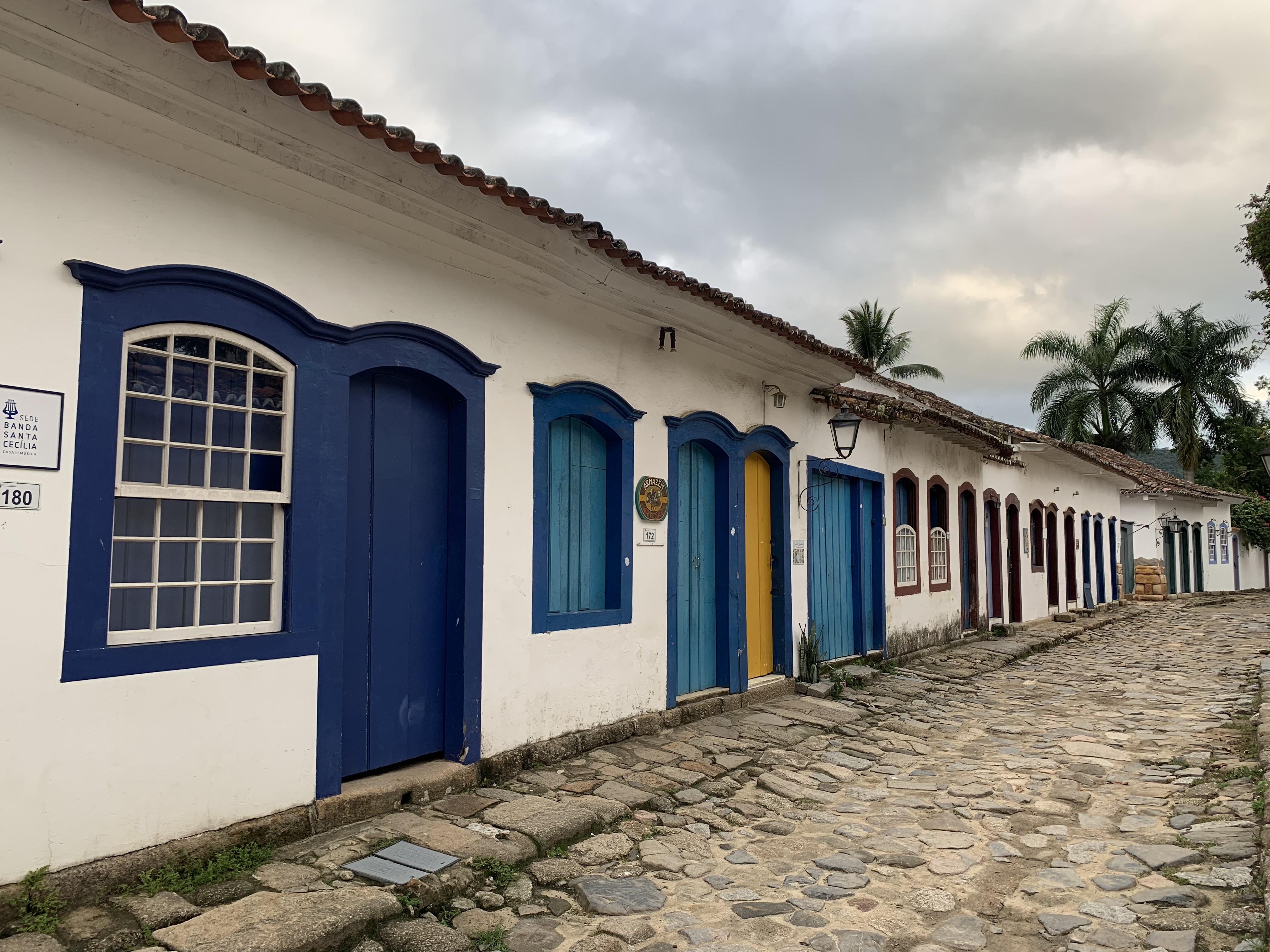 Uma ruela de paralelepípedos em Paraty que se perde ao longe com uma fileira de edifícios coloniais, suas portas pintadas em tons de azul