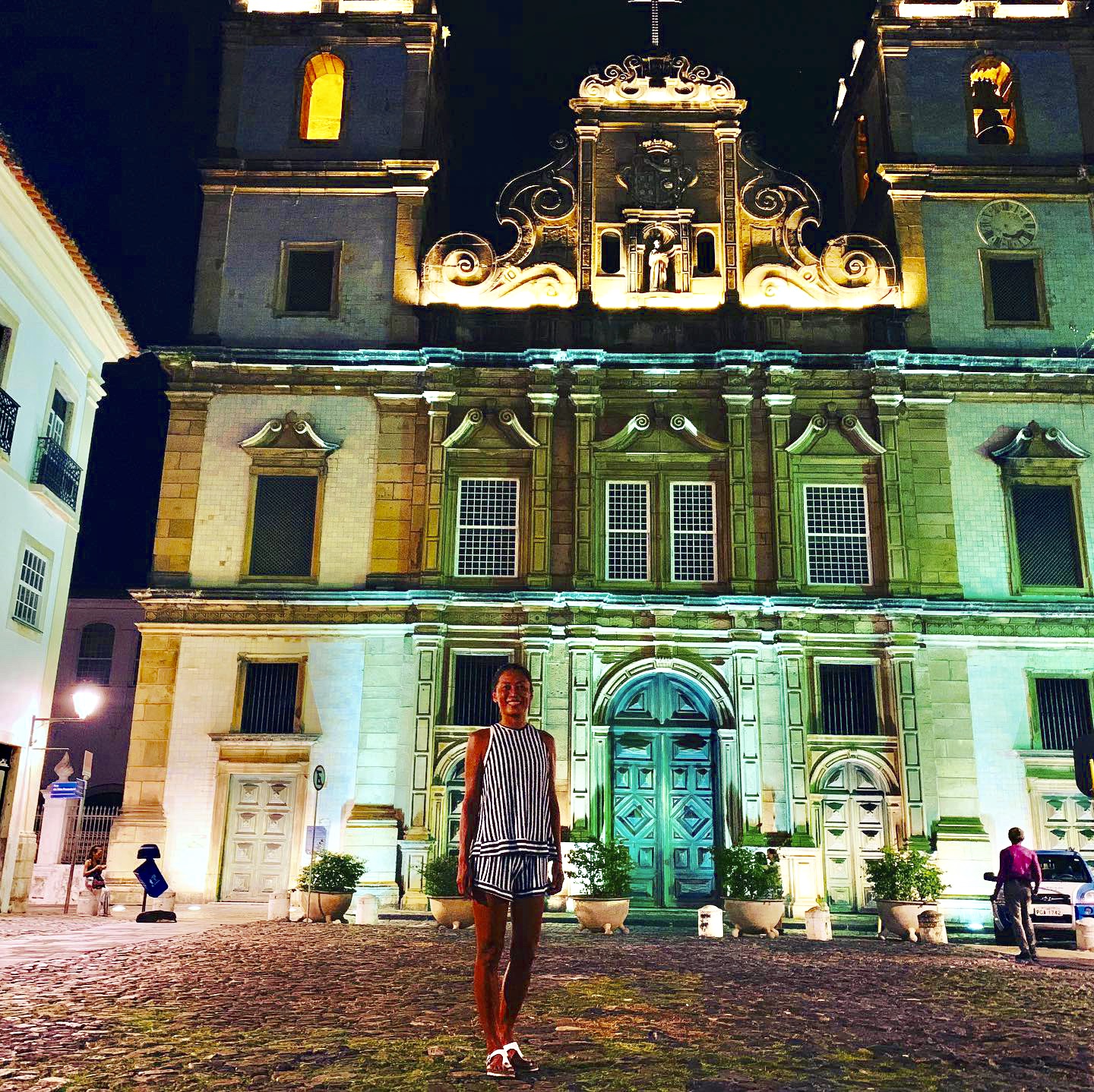 Yuka in front of an illuminated baroque church in Pelourinho at night