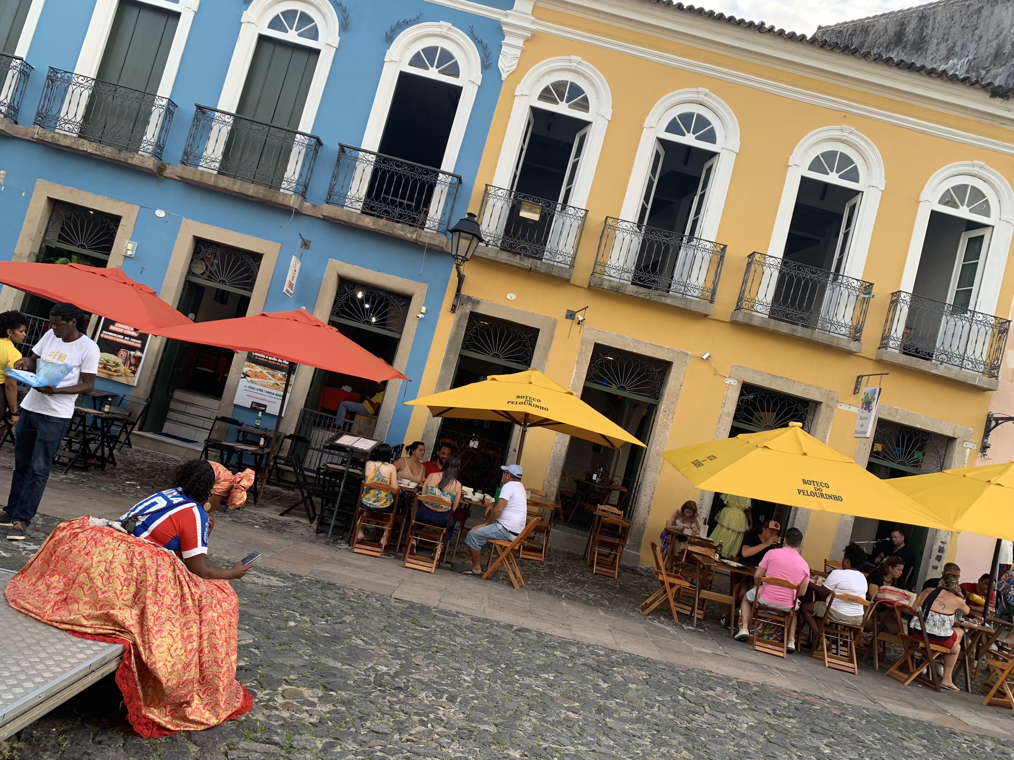 A café terrace with a woman in traditional Bahian dress