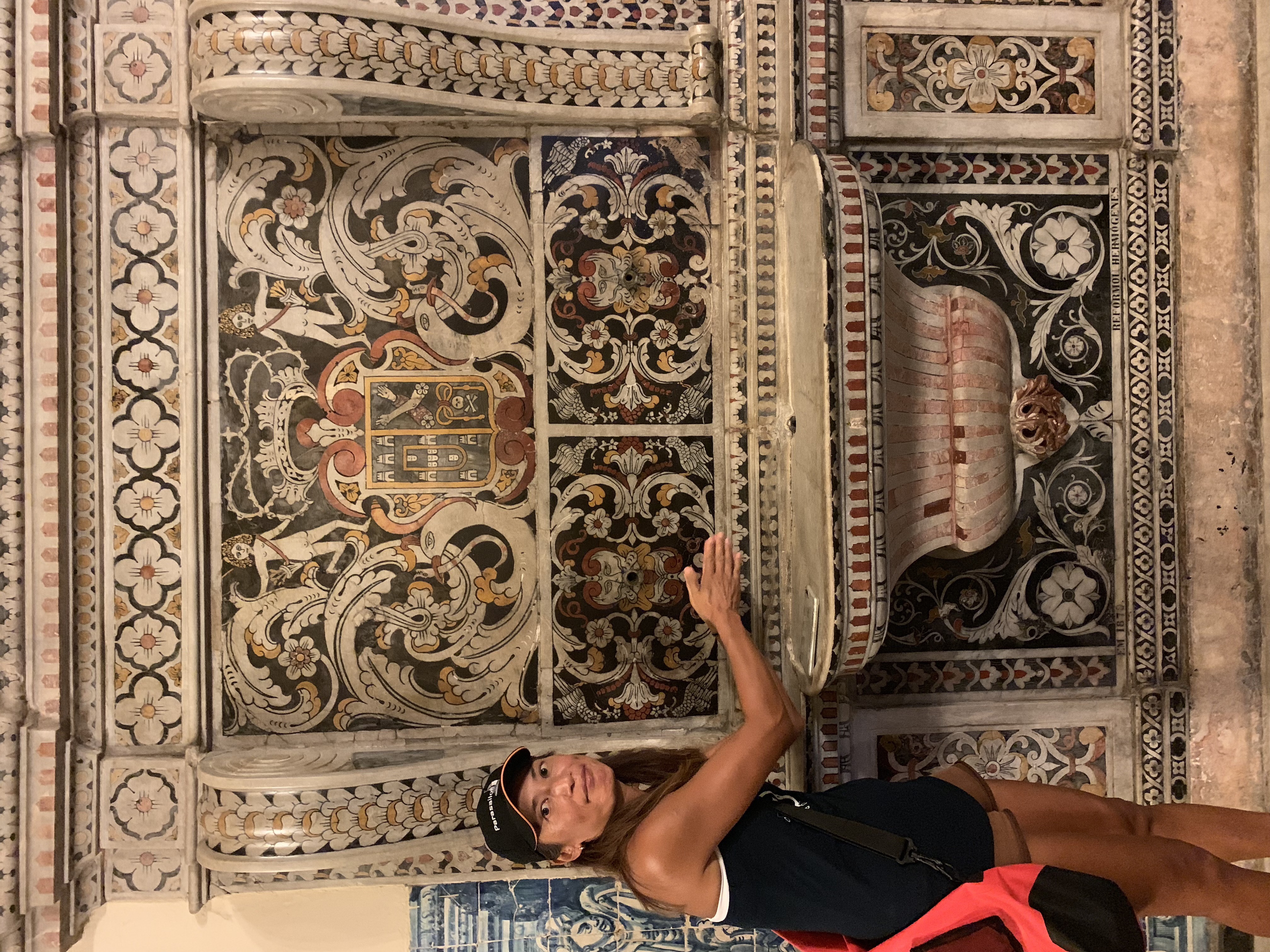 Yuka pointing at heraldic azulejo panels in the São Francisco cloister