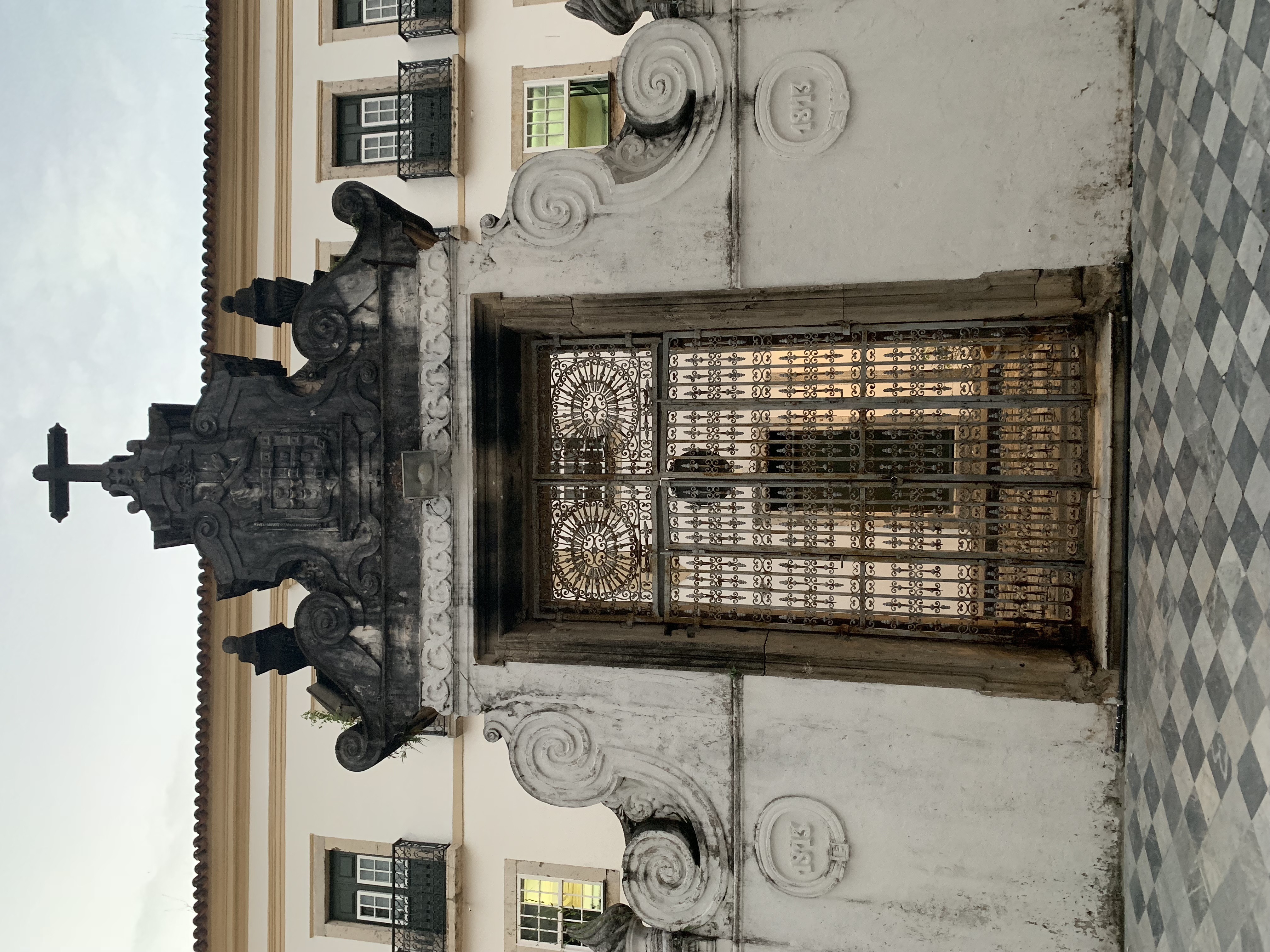 A white baroque church exterior with an ornate iron gate