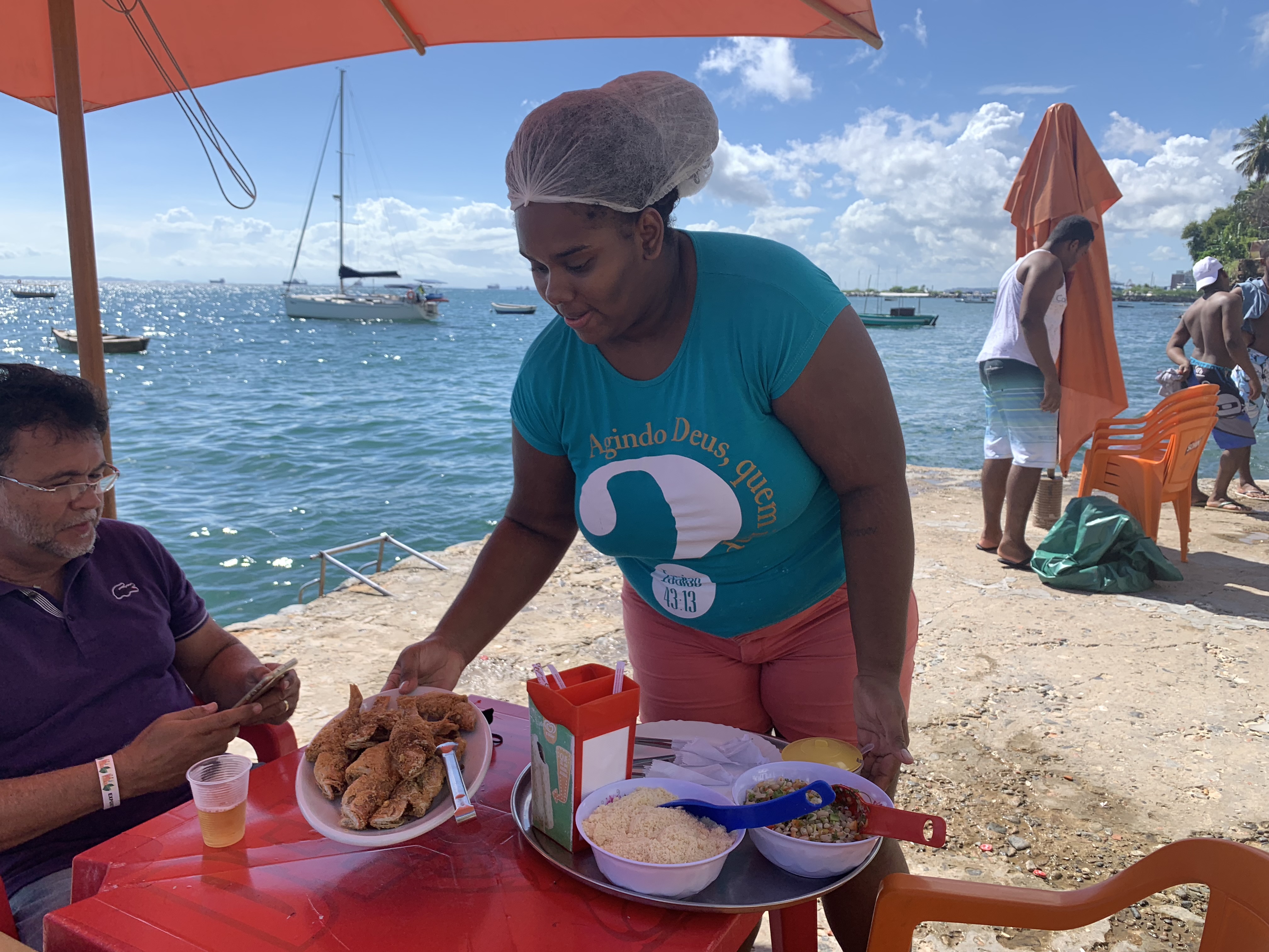 A waitress serves fried fish at a waterfront stall