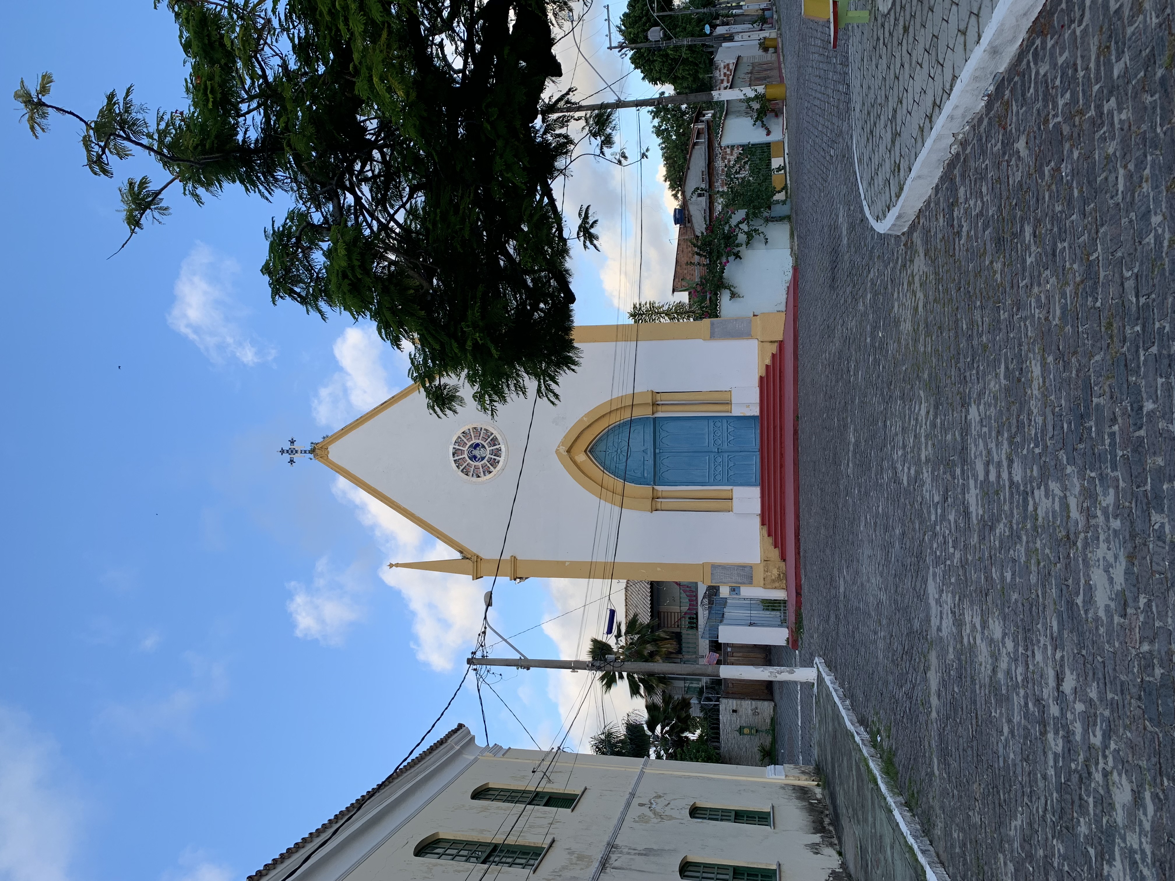 A small white and yellow colonial church with a triangular gable