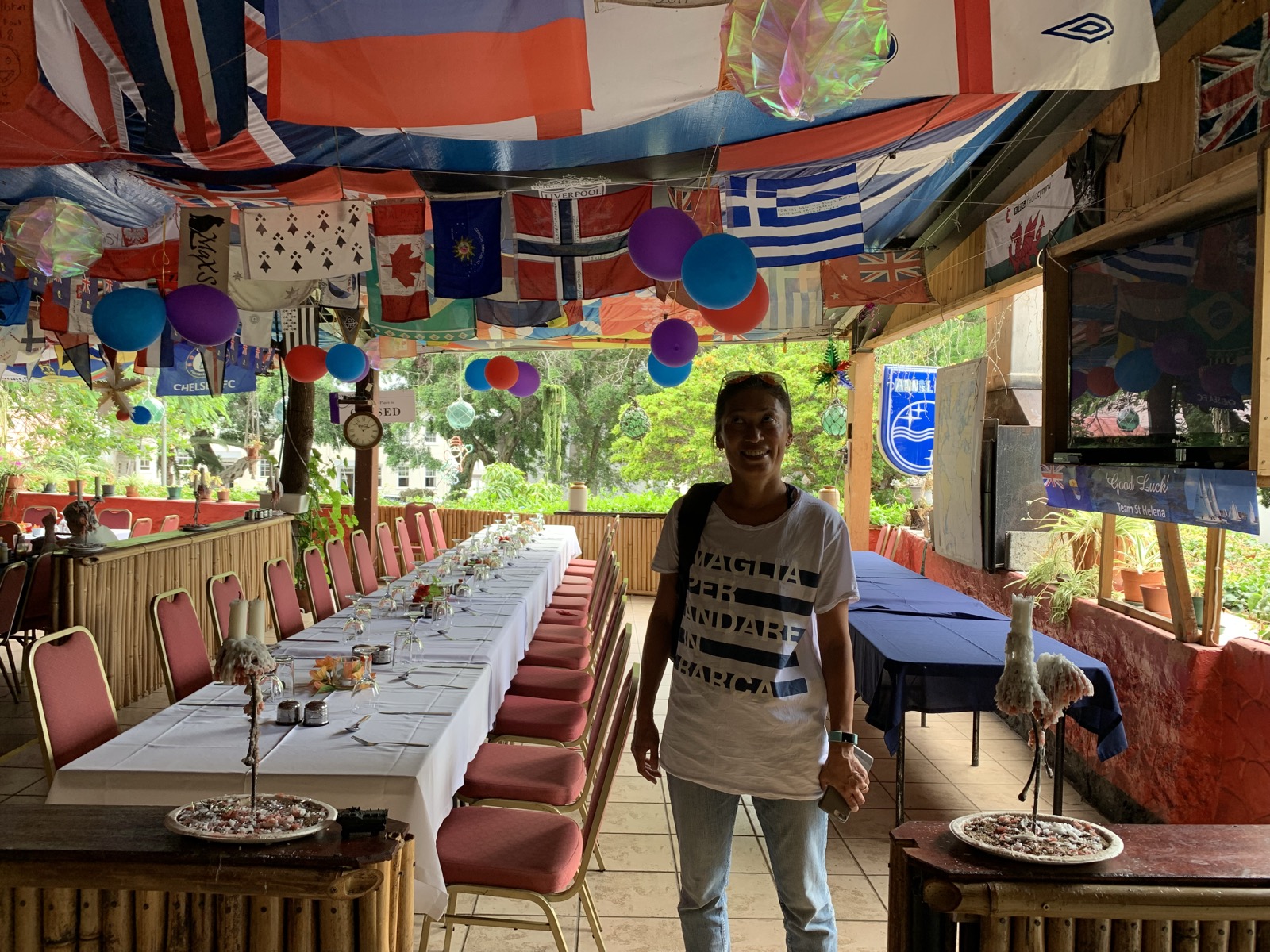 Yuka inside Anne's Place, the ceiling covered in international flags and yacht burgees from sailors who have passed through