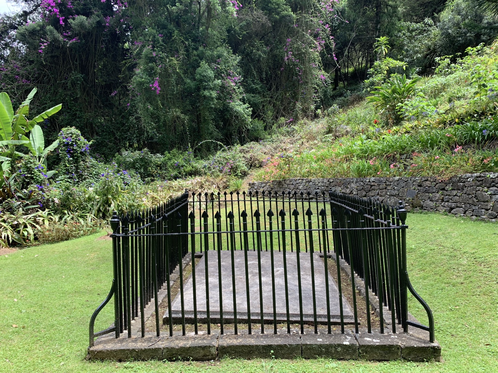 Napoleon's original tomb — a stone slab enclosed by black iron railings surrounded by lush tropical garden