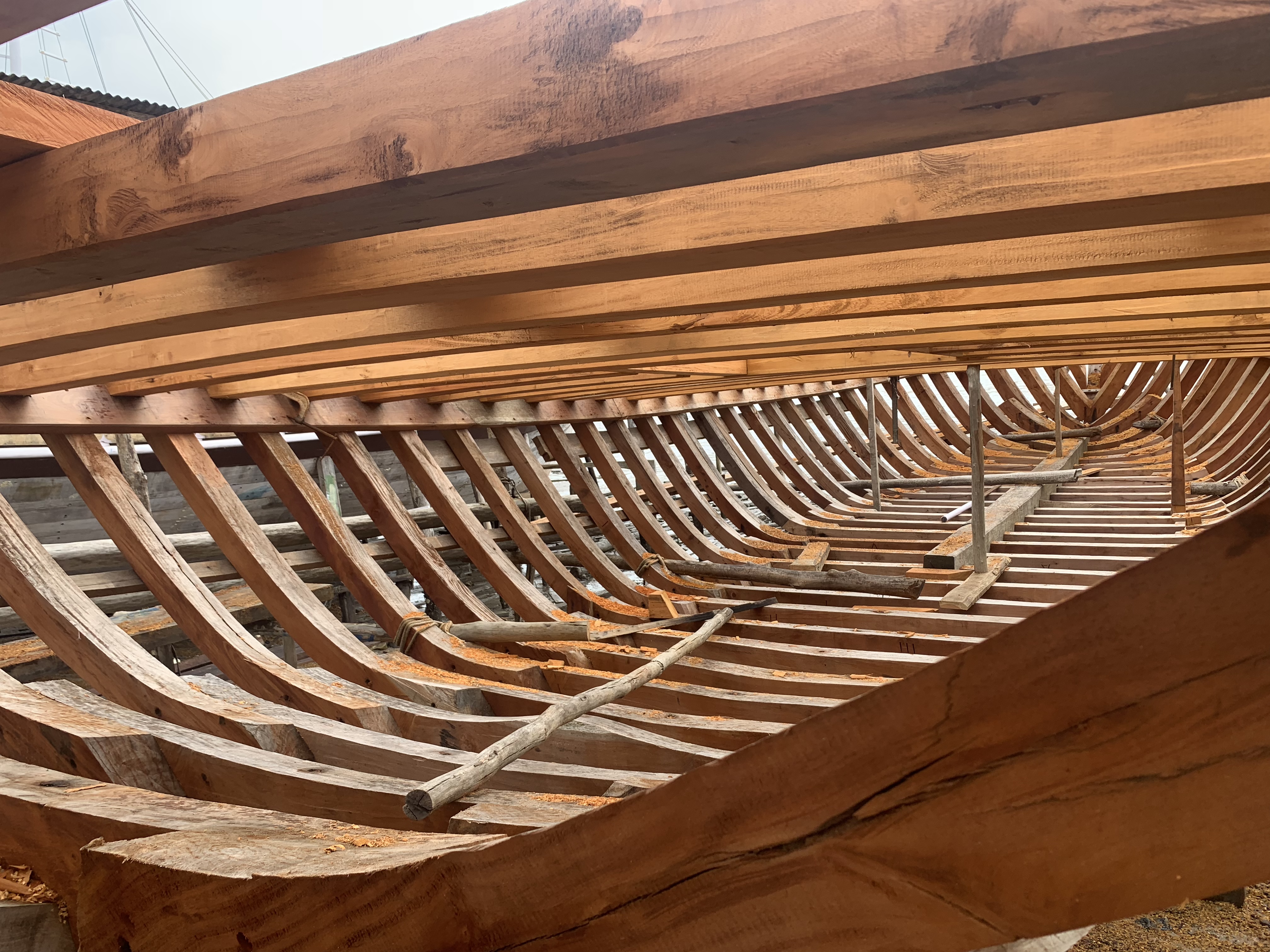 Looking along the interior ribbing of a wooden hull under construction, showing the curved frames receding into the distance